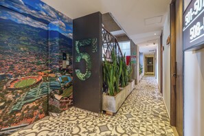 A hallway with a cityscape mural, a floor number sign, and a plant planter. - Hotel Appartments Con Piscina (Medellín)