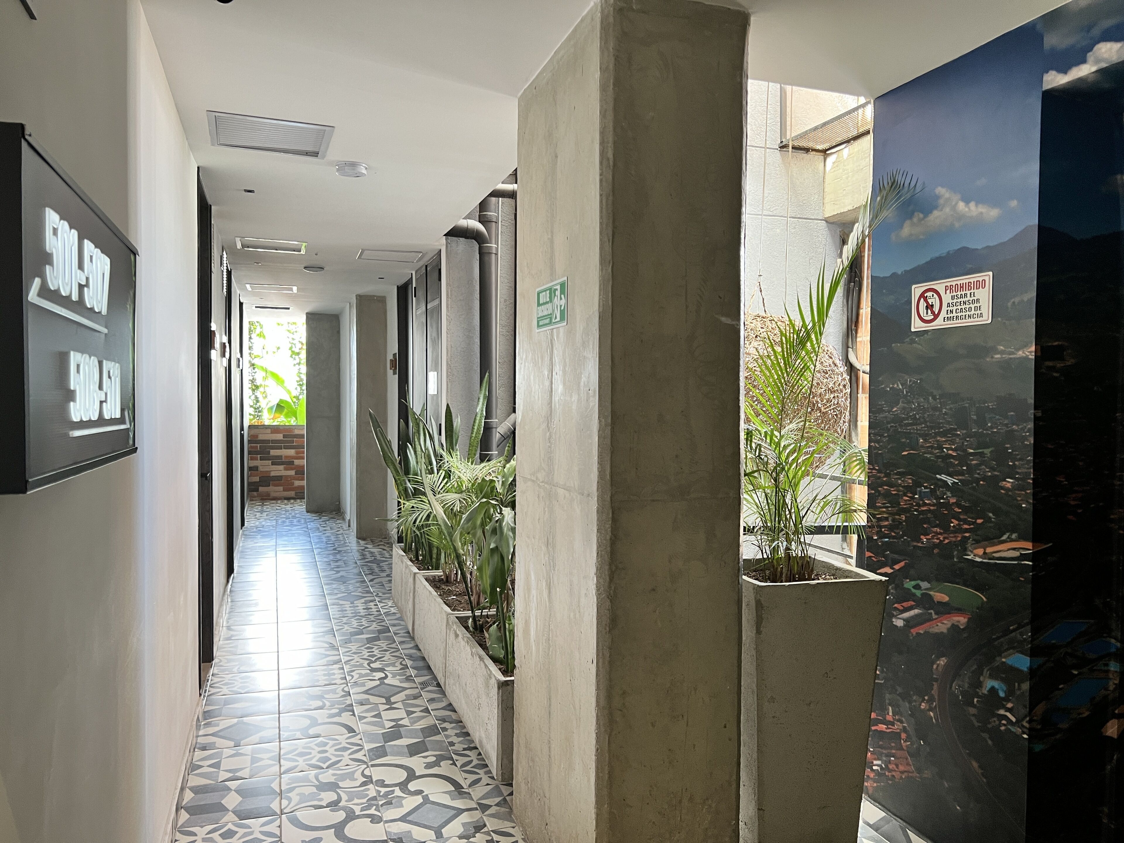 A hallway with patterned floor tiles, a concrete pillar, and a wall-mounted sign.