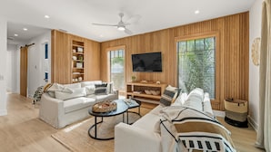 A modern living room with a sofa set, a coffee table, and a TV mounted on the wall.