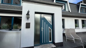 Un edificio moderno con una porta blu caratteristica, pareti bianche e un tetto spiovente.