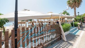 Un bar de playa con valla de madera y sombrillas.