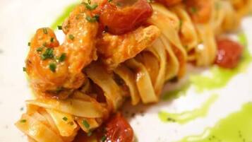 Um prato de massa com camarão e tomate.