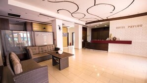 Un hall de hotel con mostrador de recepción, un sofá y una mesa de centro.
