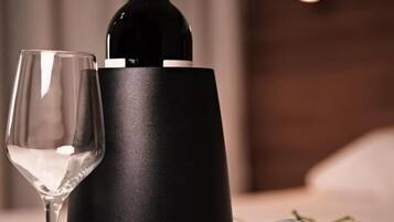 Uma garrafa de vinho, uma taça de vinho e um jarro sobre uma mesa com flores.