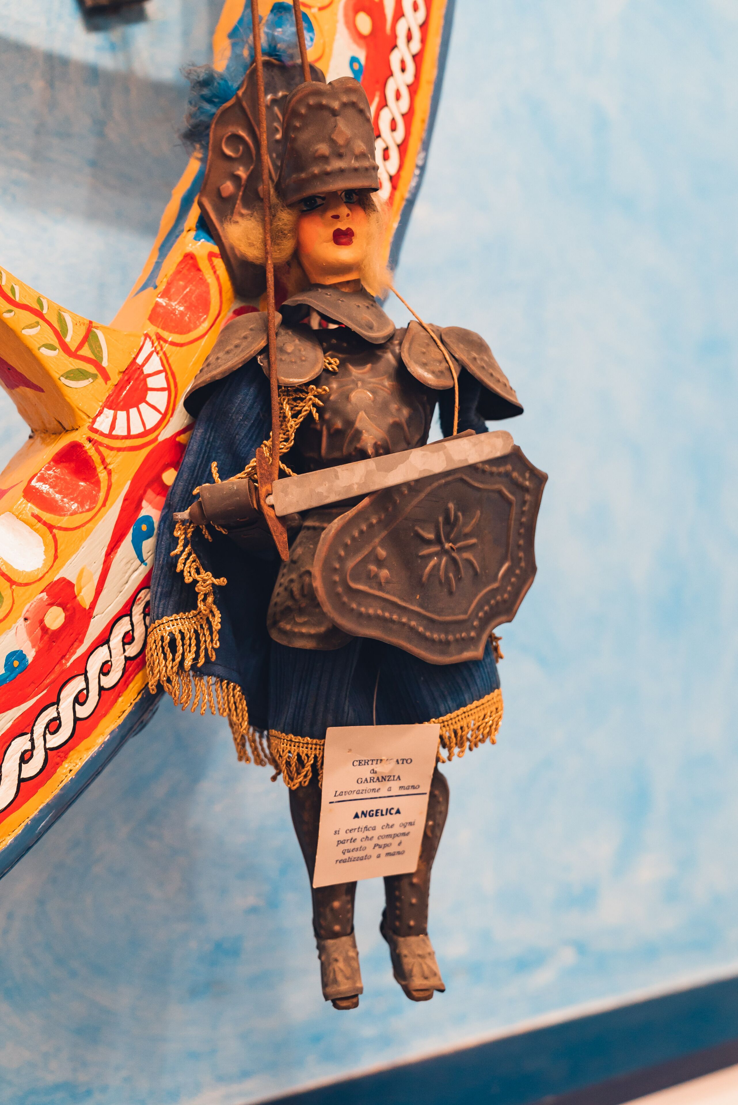 A decorative figure with a shield and armor, mounted on a colorful structure.