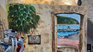 A room with a rustic stone wall, a potted plant, a vase, and a painting of a coastal scene. - macchiamediterrane (Castellammare del Golfo)