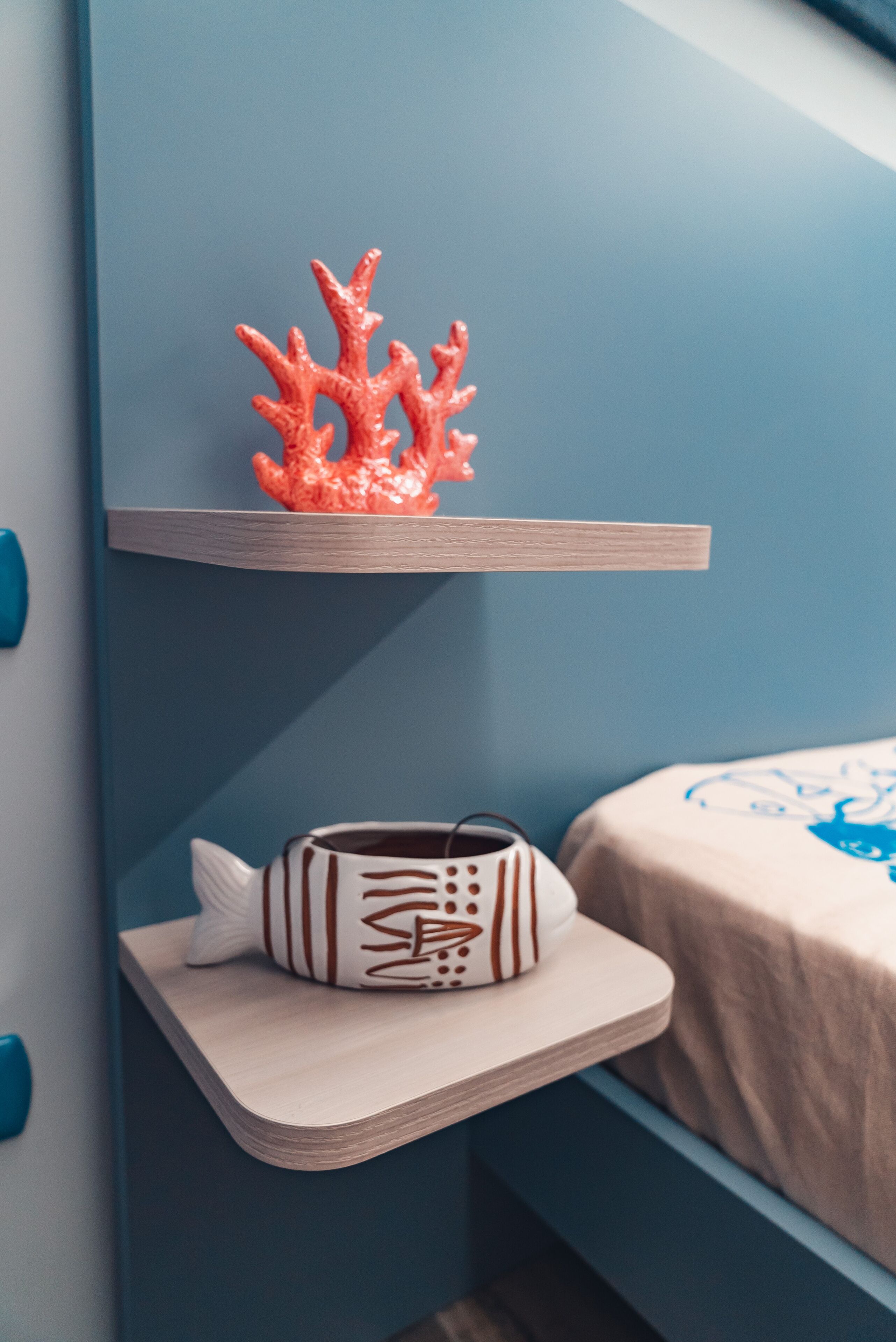 A bedroom with a bed, a nightstand, and a shelf with decorative items.