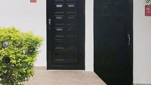 A building with a black door, a small window, and a red emergency exit sign. - Santo Domingo Centro Vacacional (Jerusalén)
