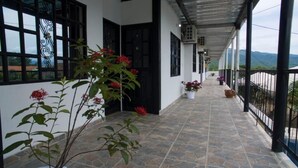 A covered corridor with tiled flooring, black-framed windows, and potted plants. - Santo Domingo Centro Vacacional (Jerusalén)