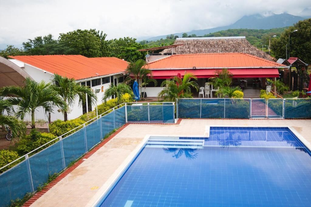 Una piscina con superficie de agua azul cristalina, rodeada por una valla de vidrio.