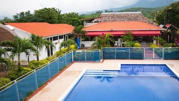 Una piscina con superficie de agua azul cristalina, rodeada por una valla de vidrio.