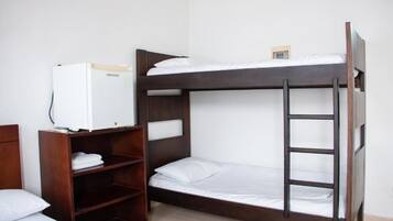 A bunk bed room with a wooden ladder, a small shelf unit, and a white refrigerator.