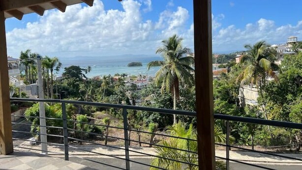 Un balcon avec vue sur la mer, les palmiers et les bâtiments.