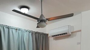 Un lit simple avec un cadre en bois, un ventilateur de plafond et un appareil de climatisation fixé au mur.