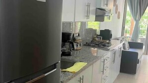 Une cuisine moderne avec des meubles blancs, un réfrigérateur en acier inoxydable et un plan de travail en granit.