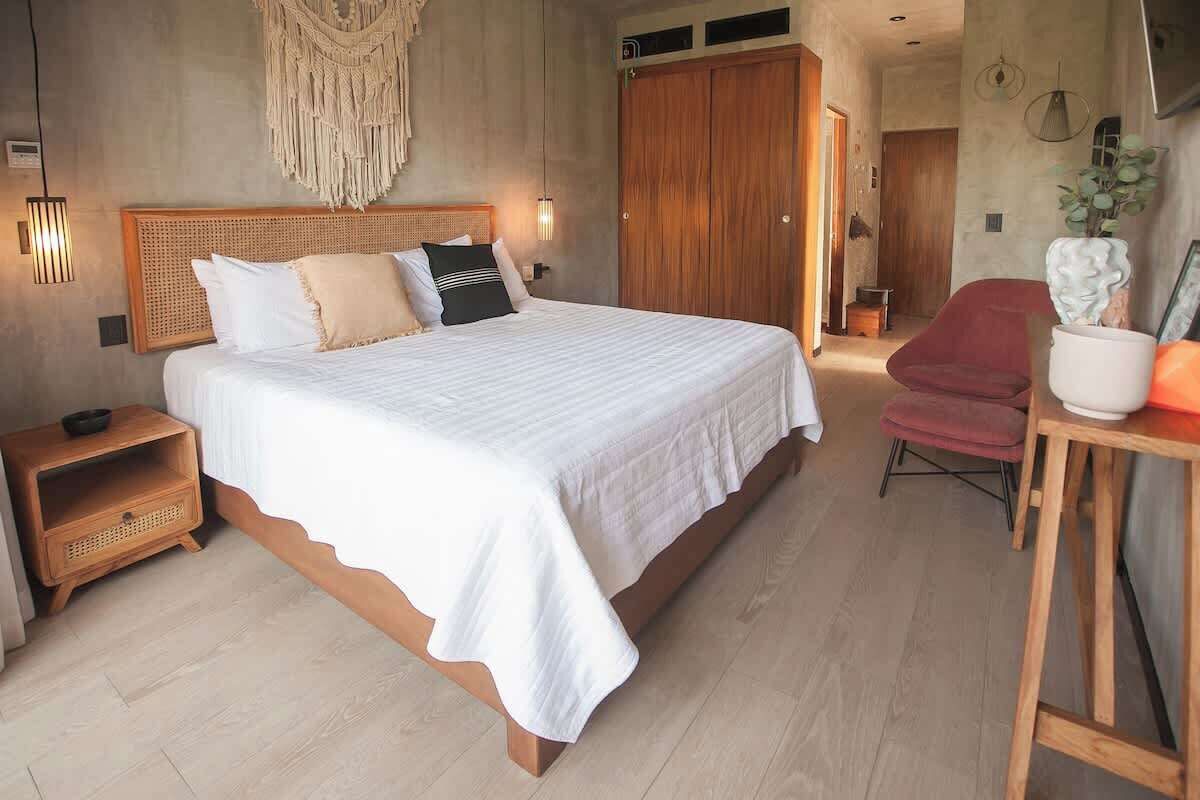Camera da letto con un letto grande, una testiera in legno, comodini, una sedia rossa e un armadio in legno.