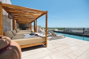 Un espace de détente aménagé sur le toit, avec une pergola en bois, des sièges confortables et une piscine.