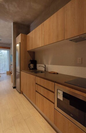 Une cuisine moderne avec des meubles en bois, un évier en acier inoxydable et un four encastré.
