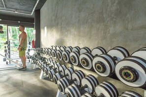 Une salle de sport avec plusieurs rangées de haltères et d'appareils de musculation.