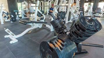 Una palestra con attrezzature per l'allenamento della forza, tra cui una panca per pesi e un espositore per manubri.