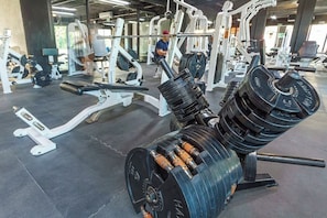 Une salle de sport équipée de matériel de musculation, notamment un banc de développé couché et un porte-haltères.