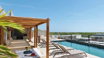 Una terrazza sul tetto con piscina, poltrone relax e un pergolato in legno.