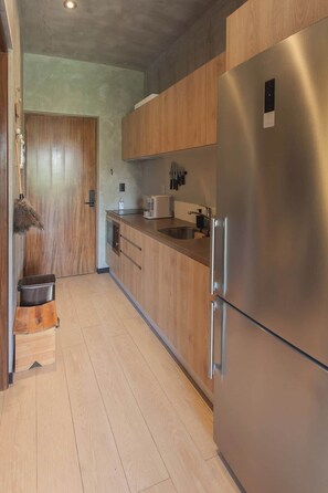 Une cuisine moderne avec des meubles en bois, un réfrigérateur en acier inoxydable et une machine à café.