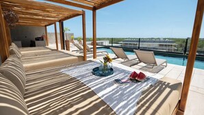 En takterrass med en loungeyta, en pool, solstolar och en soffa.