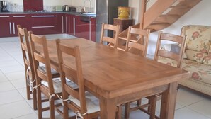 Ein Essbereich mit Holztisch und Stühlen, im Hintergrund eine Küche und eine Treppe.
