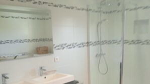 Ein Badezimmer mit einem Doppelwaschtisch, einer Duschkabine aus Glas und einem gefliesten Boden.