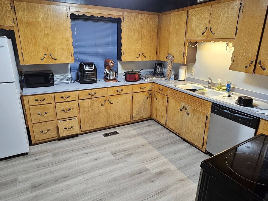 Una cocina con armarios de madera, un refrigerador blanco, una cafetera y un fregadero.
