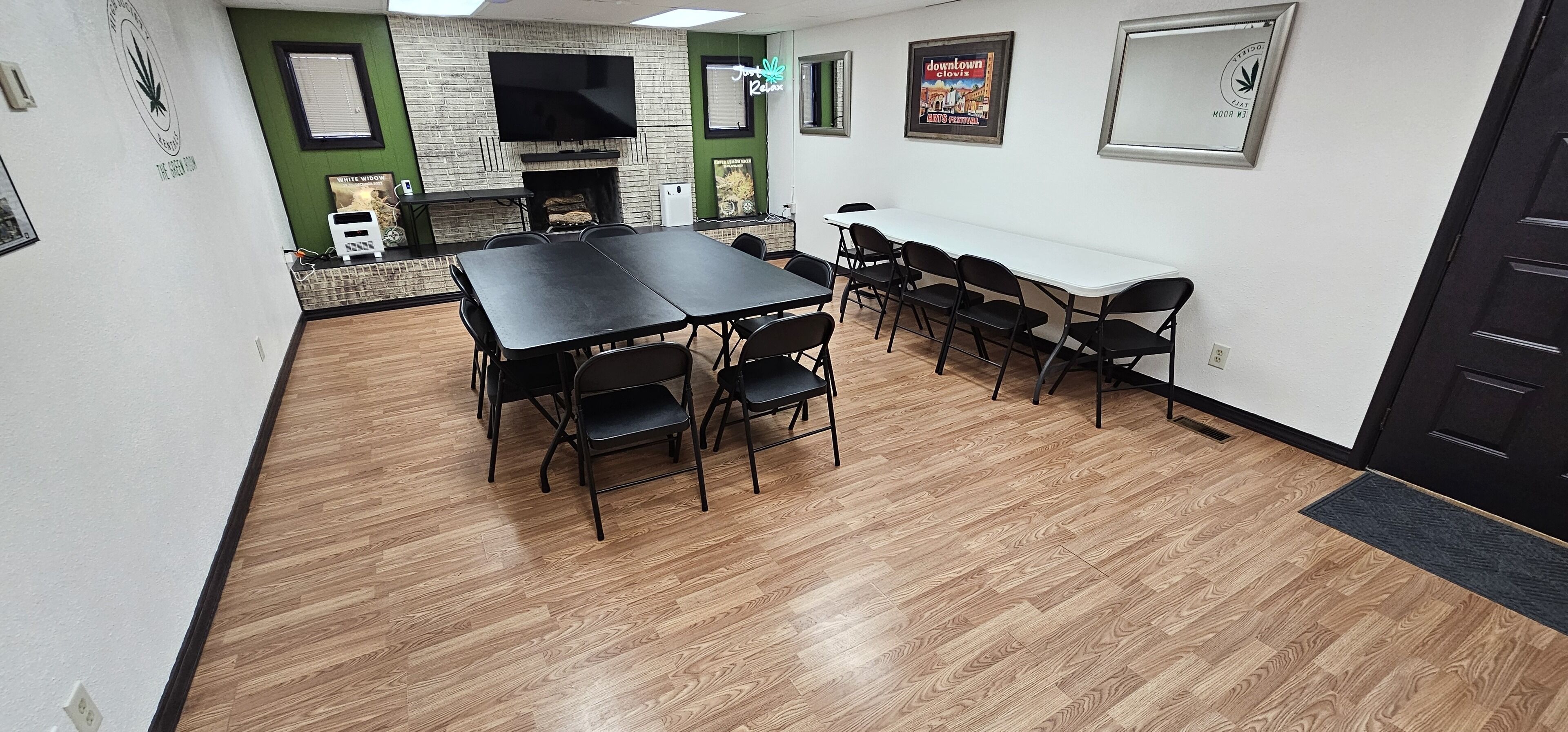 A conference room with a long table and chairs, a fireplace, and a television on the wall.