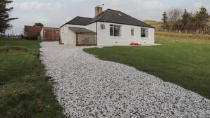 A white house with a gravel driveway leading to a garage. - Taigh Neilag (Strath)