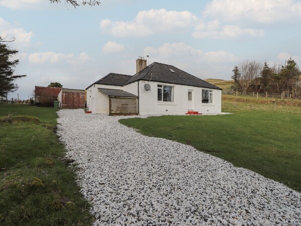A white house with a gravel driveway leading to a garage. - Taigh Neilag (Strath)