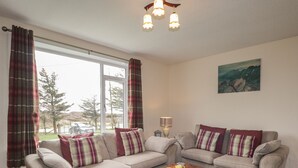 A living room with two sofas, a wooden coffee table, and a painting on the wall. - Taigh Neilag (Strath)