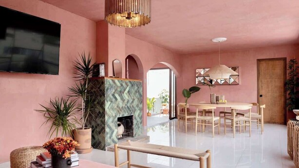 Ein wohnzimmer in Rosa mit Fernseher, Kamin, Esstisch und Sitzgruppe.