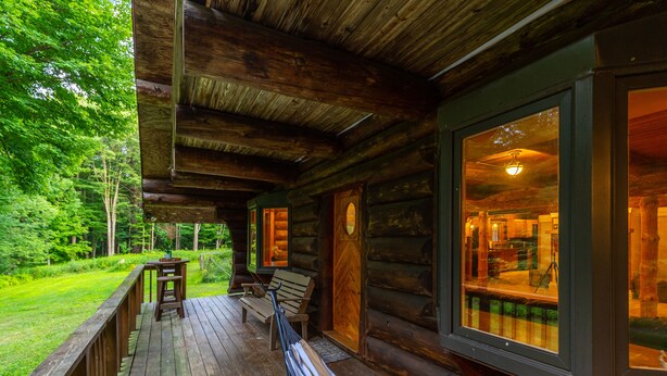 A wooden cabin with a deck, a bench, and a table. - Log Cabin with Private Indoor Heated Pool-Hot Tub-firepit-Game Room-100 acres (Homer)