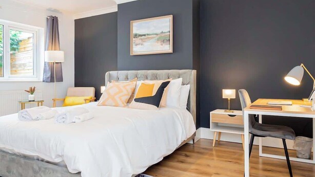 Un dormitorio moderno con una cama grande, mesitas de noche, un escritorio y una silla.