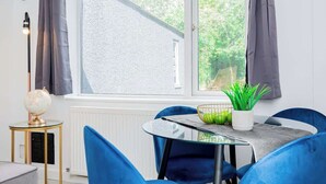 Un comedor moderno con una mesa redonda, sillas azules, un globo terráqueo sobre una mesita auxiliar y vistas al exterior con vegetación.