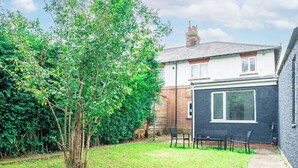 A residential property with a small garden, a brick house, and a black exterior wall.
