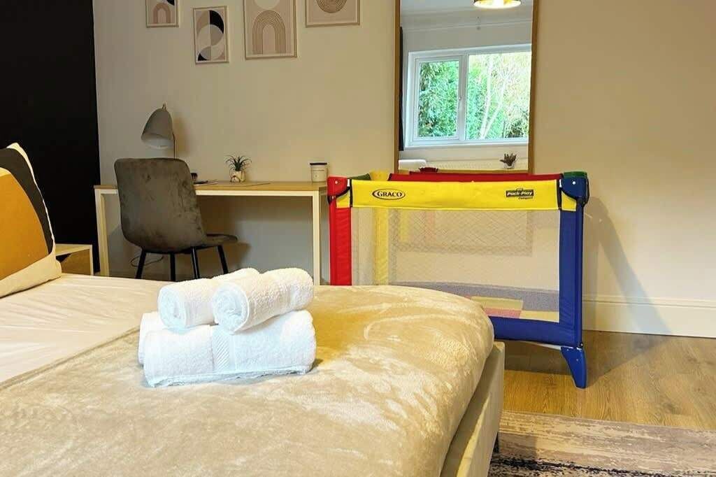 Ein Hotelzimmer mit einem Bett, einem Schreibtisch mit Computer, einem Stuhl und einem Fenster mit Blick ins Grüne.