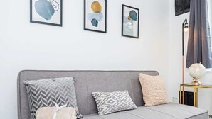 Un sofá gris con cojines estampados, un globo terráqueo sobre una mesita y arte abstracto en la pared.