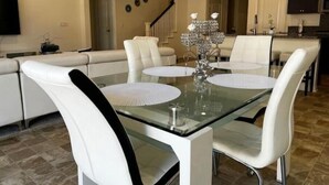A dining area with a glass table, white chairs, and a chandelier. - Charming 4BR/3BA Home in Menifee (Menifee)