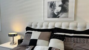 A neatly made bed with a tufted headboard, a bedside lamp, and a framed artwork on the wall. - Charming 4BR/3BA Home in Menifee (Menifee)