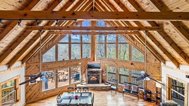 A spacious wooden interior with a high ceiling, large windows, a fireplace, and a dining area. - *Spacious 4BD Lodge w/ HOT TUB! Pool + Mtn Views!* (Sevierville)