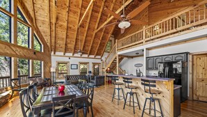 A spacious wooden interior with a dining area, kitchen, and a balcony. - *Spacious 4BD Lodge w/ HOT TUB! Pool + Mtn Views!* (Sevierville)