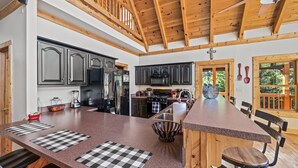 A spacious kitchen with granite countertops, dark cabinetry, and a large island with seating. - *Spacious 4BD Lodge w/ HOT TUB! Pool + Mtn Views!* (Sevierville)