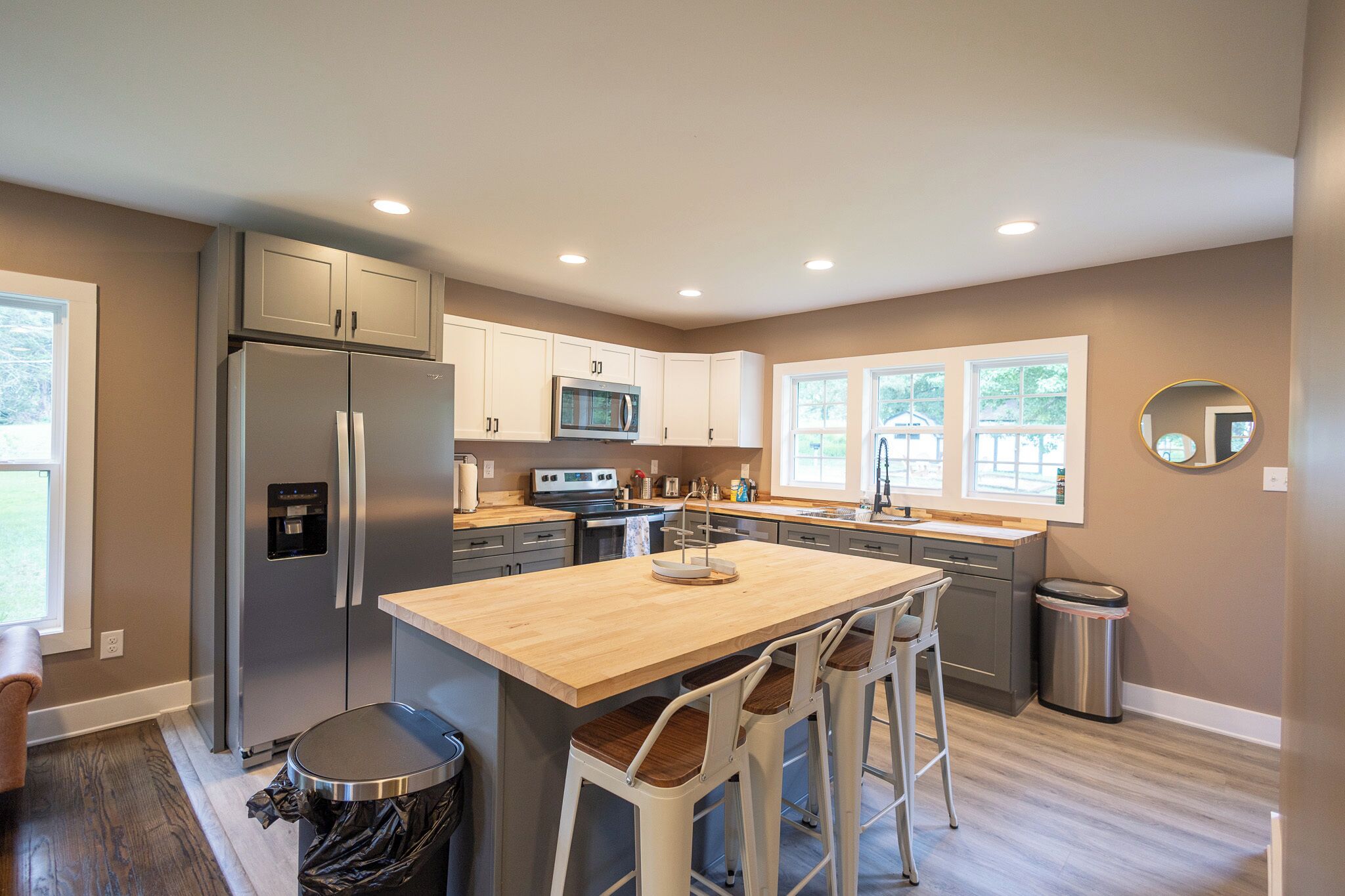 A modern kitchen with a central island, stainless steel appliances, and bar stools.