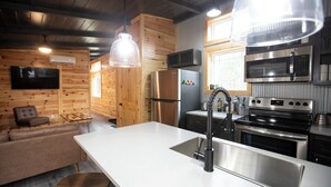 A modern kitchen with stainless steel appliances, a white countertop, and wooden walls. - The Maple Retreat at Park Mammoth (Park City)