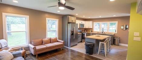 Una cocina moderna con una isla central, un refrigerador y un comedor con taburetes de bar.